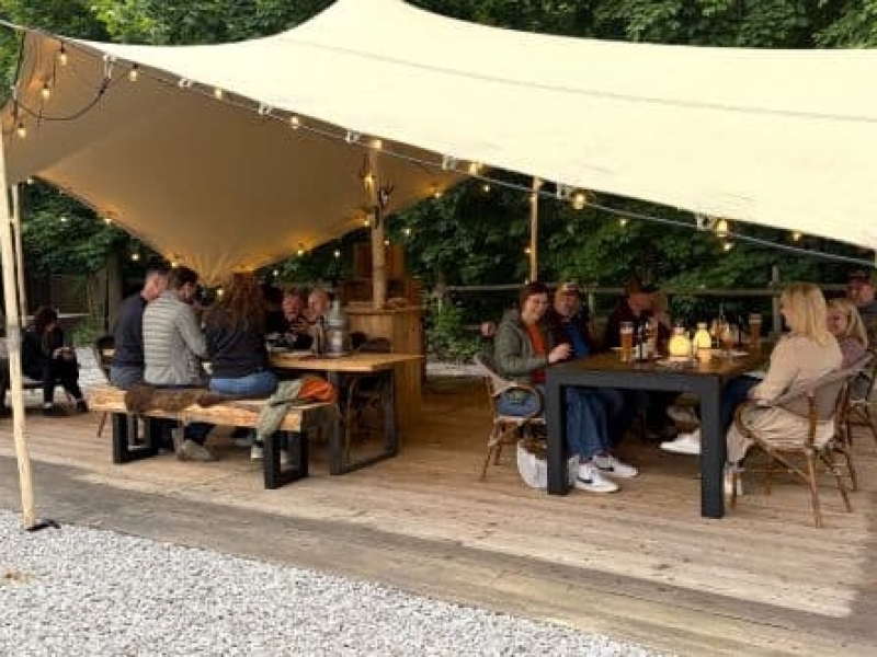 Groep gasten dineren onder de buitentent tijdens outdoor cooking avond bij Harz Hotel Iris in de Harz