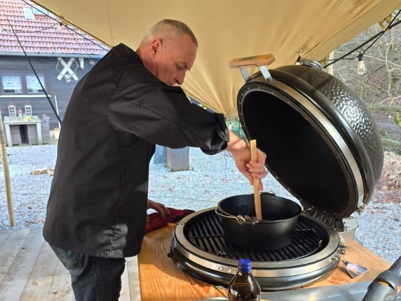 Emile, eigenaar van Harz Hotel Iris. kookt buiten op open vuur in de Harz Duitsland, sfeervolle barbecueavond met gasten