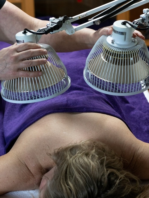 therapeut zet moxalampen klaar voor behandeling vrouw op massagetafel