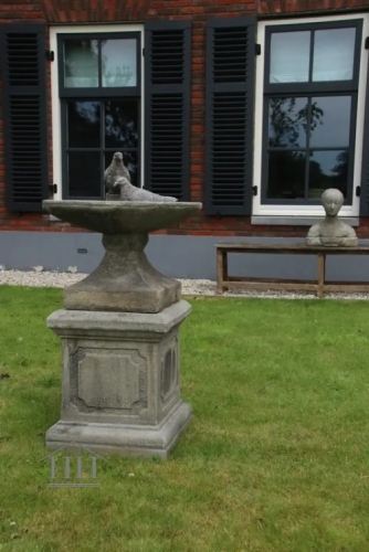 Betonnen vogelbad op sokkel met duif