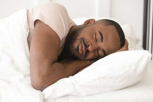 Een man ligt te slapen onder een wit dekbed