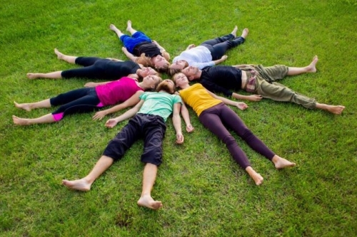 Team training waar werknemers in een bloem vorm op een grasveld liggen