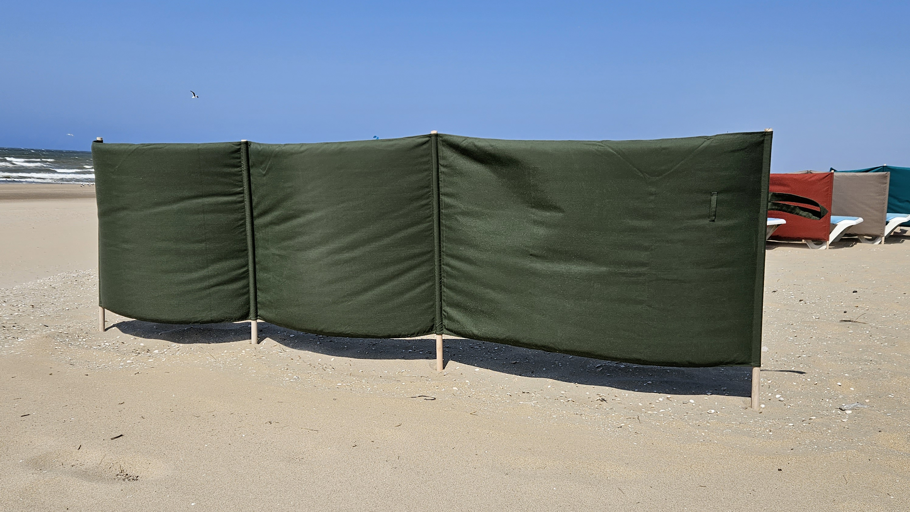 Groene stoffen windschermen voor intensief gebruik bij een beachclub