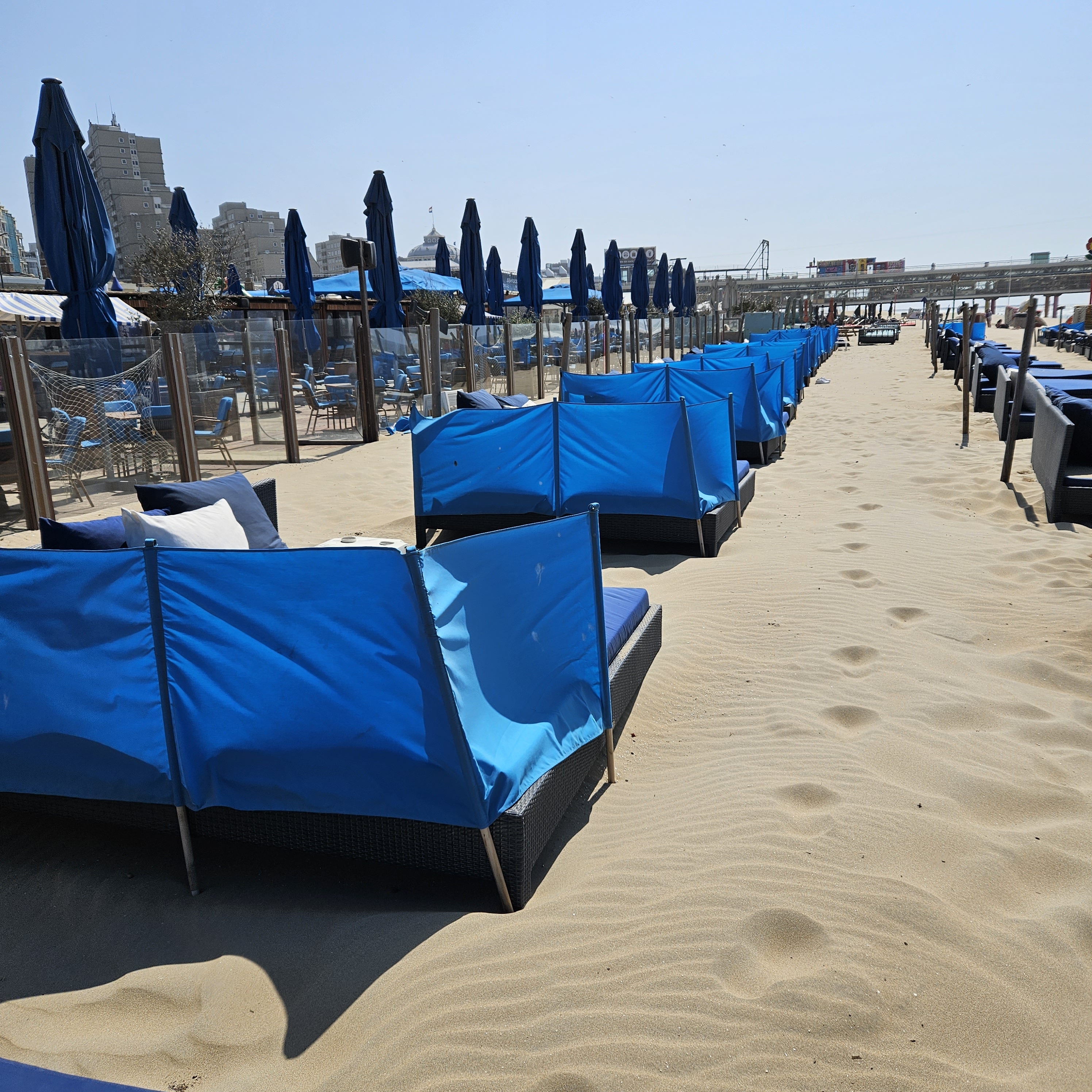 Blauwe stoffen windschermen zonder scheerlijnen bij beachclub Werelds Scheveningen