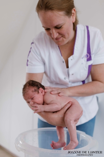 De kraamverzorgende doet de baby in de tummy tub