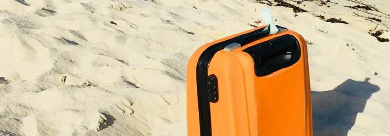 Oranje koffer op strand