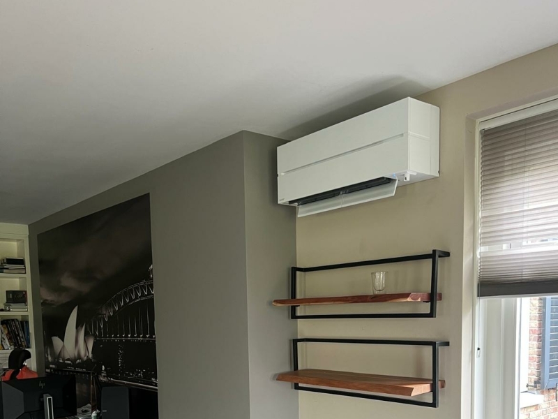 Airco voor thuis – wandmodel in woonkamer Witte wandairco geïnstalleerd in een woonkamer voor comfortabele koeling en verwarming in huis.