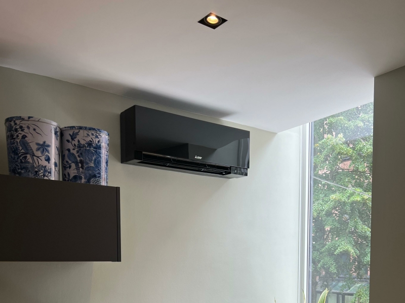 Airco voor thuis – zwarte design wandunit Zwarte wandairco geïnstalleerd in een moderne keuken, geschikt voor koelen en verwarmen in huis.