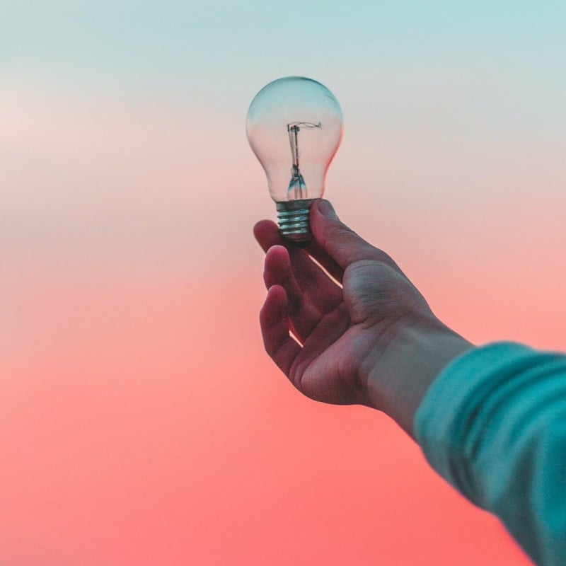 Hand met lichtpeertje tijdens zonsondergang