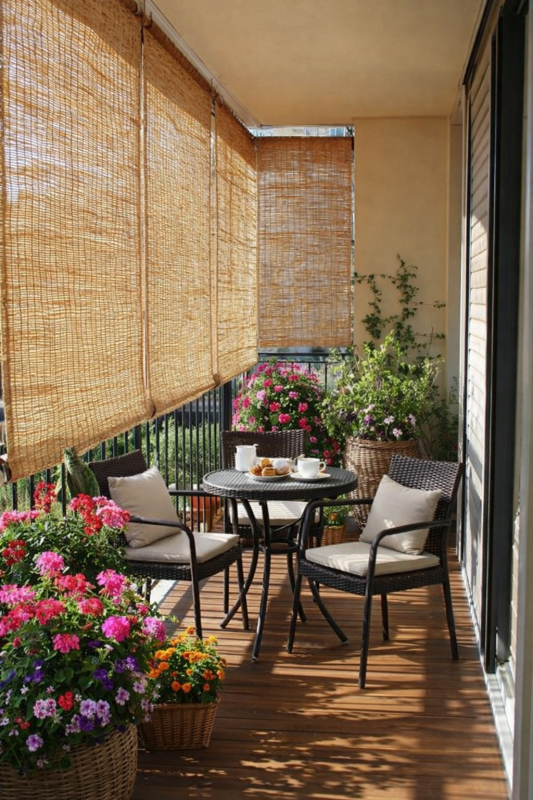 Bamboe rolgordijnen op balkon tegen inkijk met gezellig balkonsetje en kleurrijke bloemen Bamboe rolgordijnen op balkon tegen inkijk met gezellig balkonsetje en kleurrijke bloemen