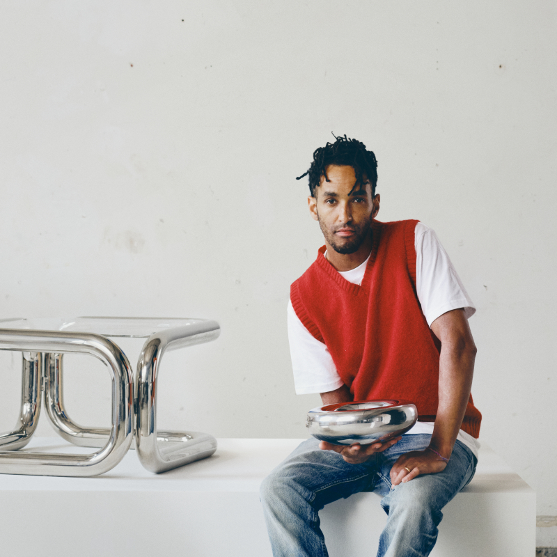 Designer met de zilverkleurige KONSTRUNDA schaal en chrome bijzettafel van IKEA