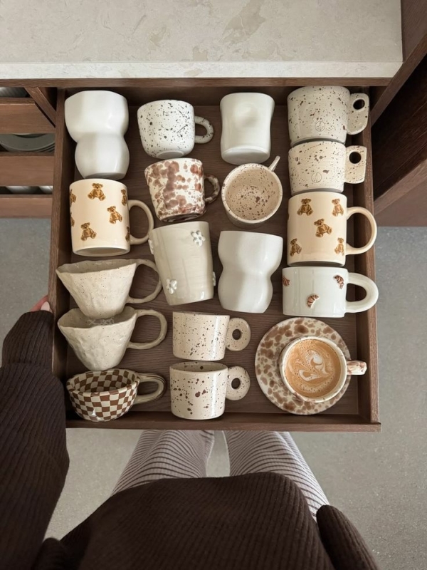 Mokken en koffiekopjes met organische vorm en glazuur, gestyled in een rustig koffiehoekje