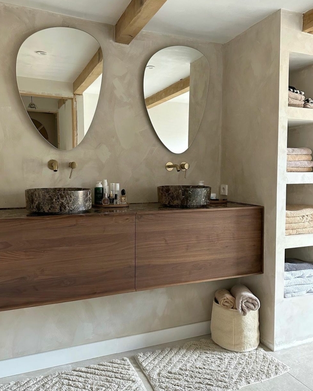 beton ciré in een badkamer met houten wastafels en organische spiegels