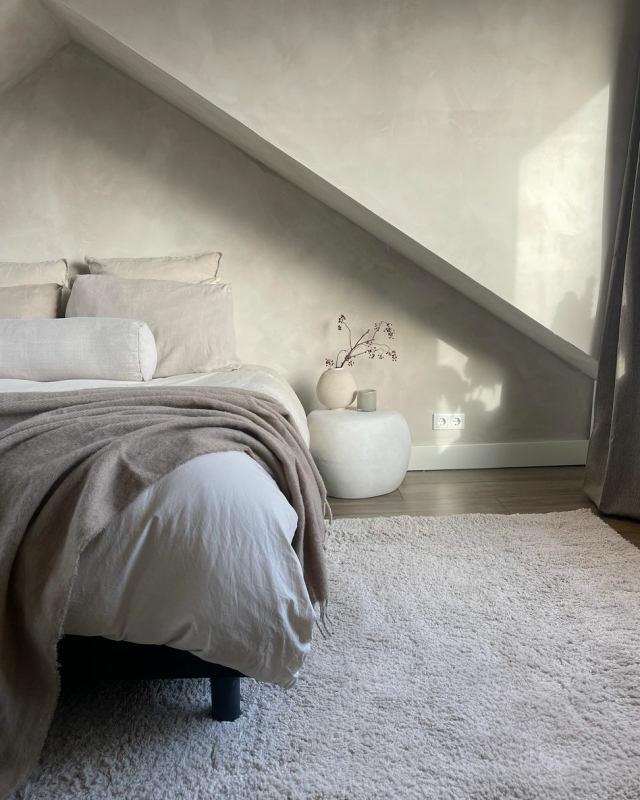 een slaapkamer met beige tinten en beton ciré