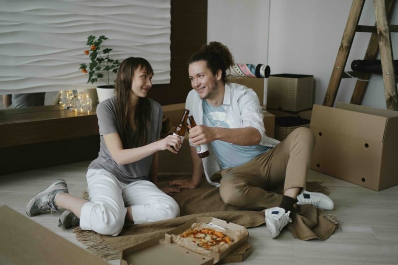 koppel viert verhuizing naar nieuwe huurwoning met pizza