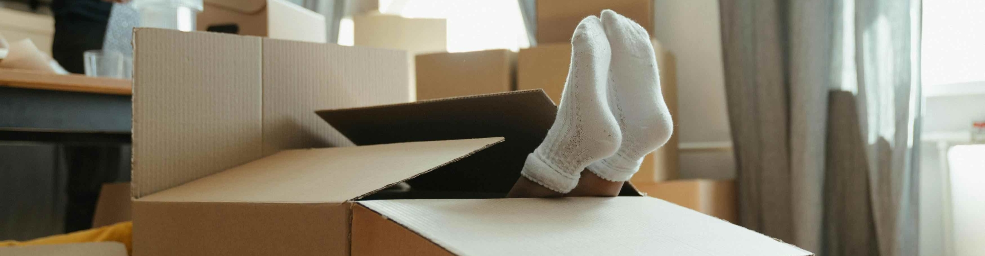 verhuisdozen in een woonkamer met een kind die zich verstopt in een verhuisdoos