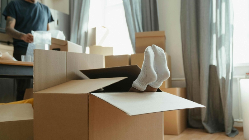 verhuisdozen in een woonkamer met een kind die zich verstopt in een verhuisdoos