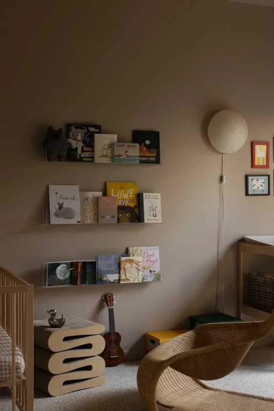 beige babykamer met boekenrek aan de muur