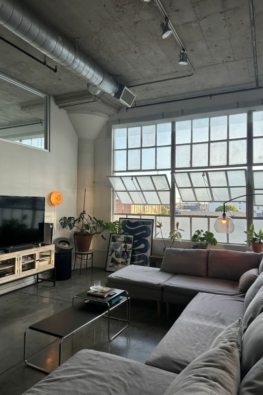 industriële woonkamer met grijze bank en grote ramen industriële woonkamer met grijze bank en grote ramen