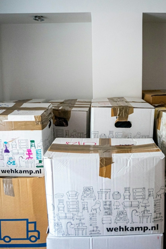 verhuisdozen staan opgestapeld in een witte kamer