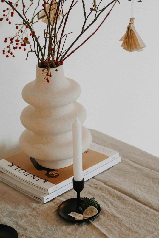 Een witte vaas staat op een linnen tafelkleed in een Scandinavisch interieur