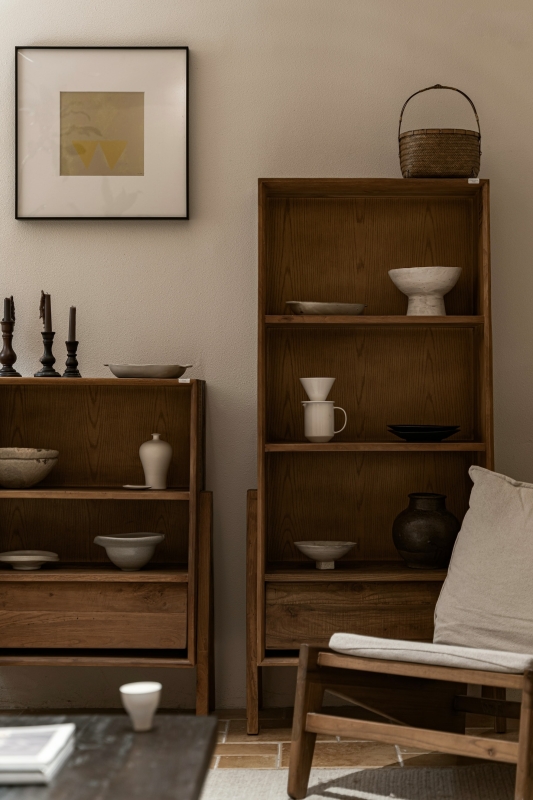 een japandi-stijl in een interieur met donkere, houten boekenkasten en houten stoel