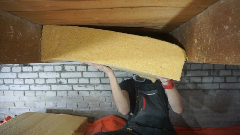 Houtvezel isolatie klemmen tussen de houten vloer balken via de kruipruimte