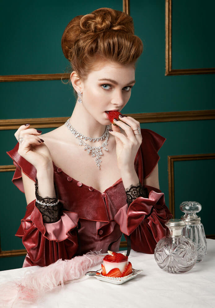 Bruidssieraden Lineargent Juwelier Leguit Mooie dame met rode jurk eet een aardbei en draagt royal sieraden voor een bruiloft