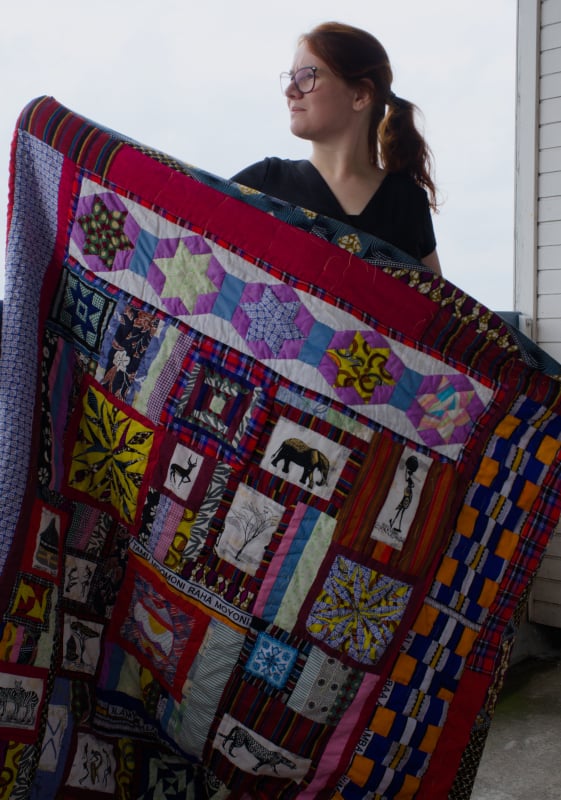 Rianne holds her kenyan quilt made with scrap fabrics and kitenge with quilt patterns designed by Rianne
