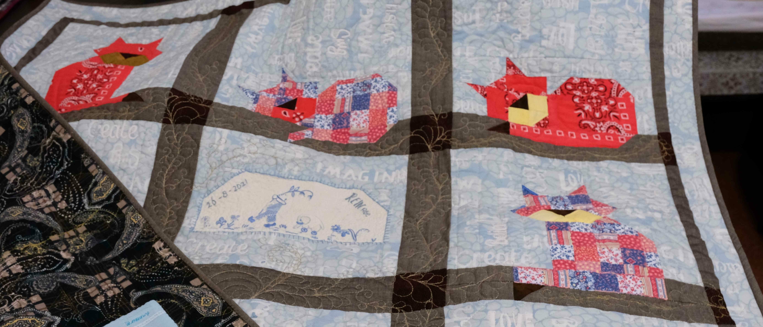 Memory baby quilt with patchwork cats and a label