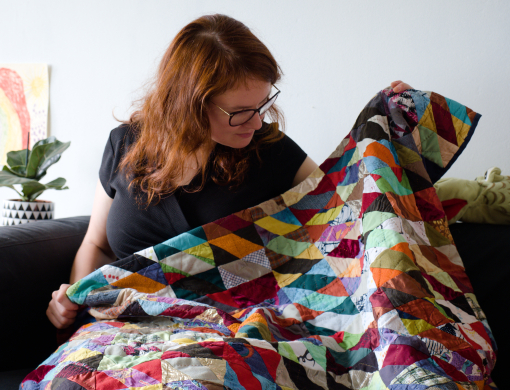 Rianne of kick-ass quilts looking at her first quilt made with donated scrap fabrics and old clothes