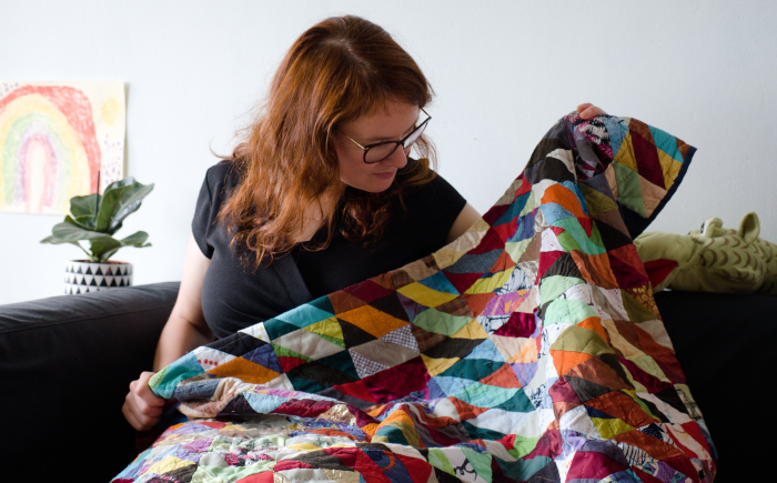 Rianne of kick-ass quilts looking at her first quilt made with donated scrap fabrics and old clothes