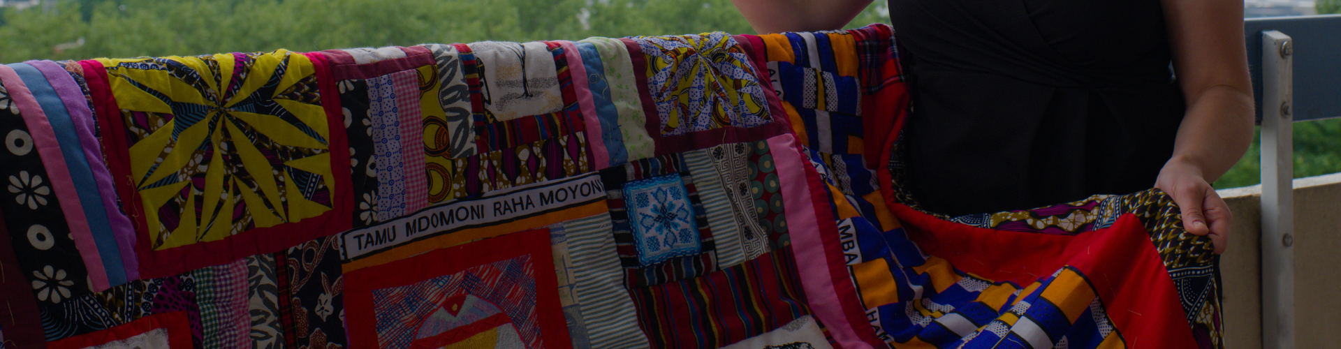 Rianne from Kick-Ass Quilts pointing to Kenya the distance with a colourful quilt made with Kitenge Kenyan fabrics