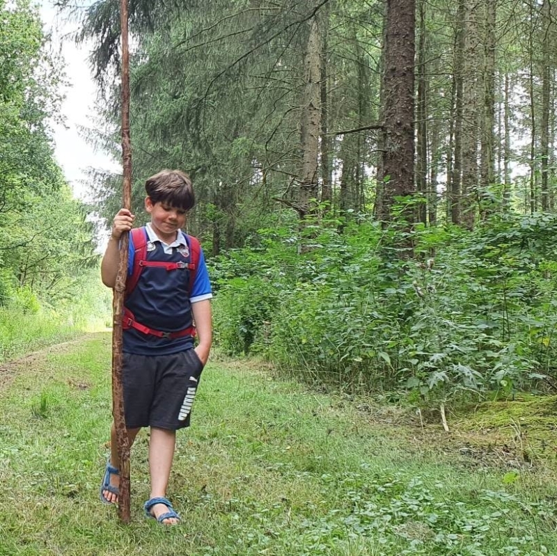 kind met rugzak loopt in de natuur tijdens een dagje weg