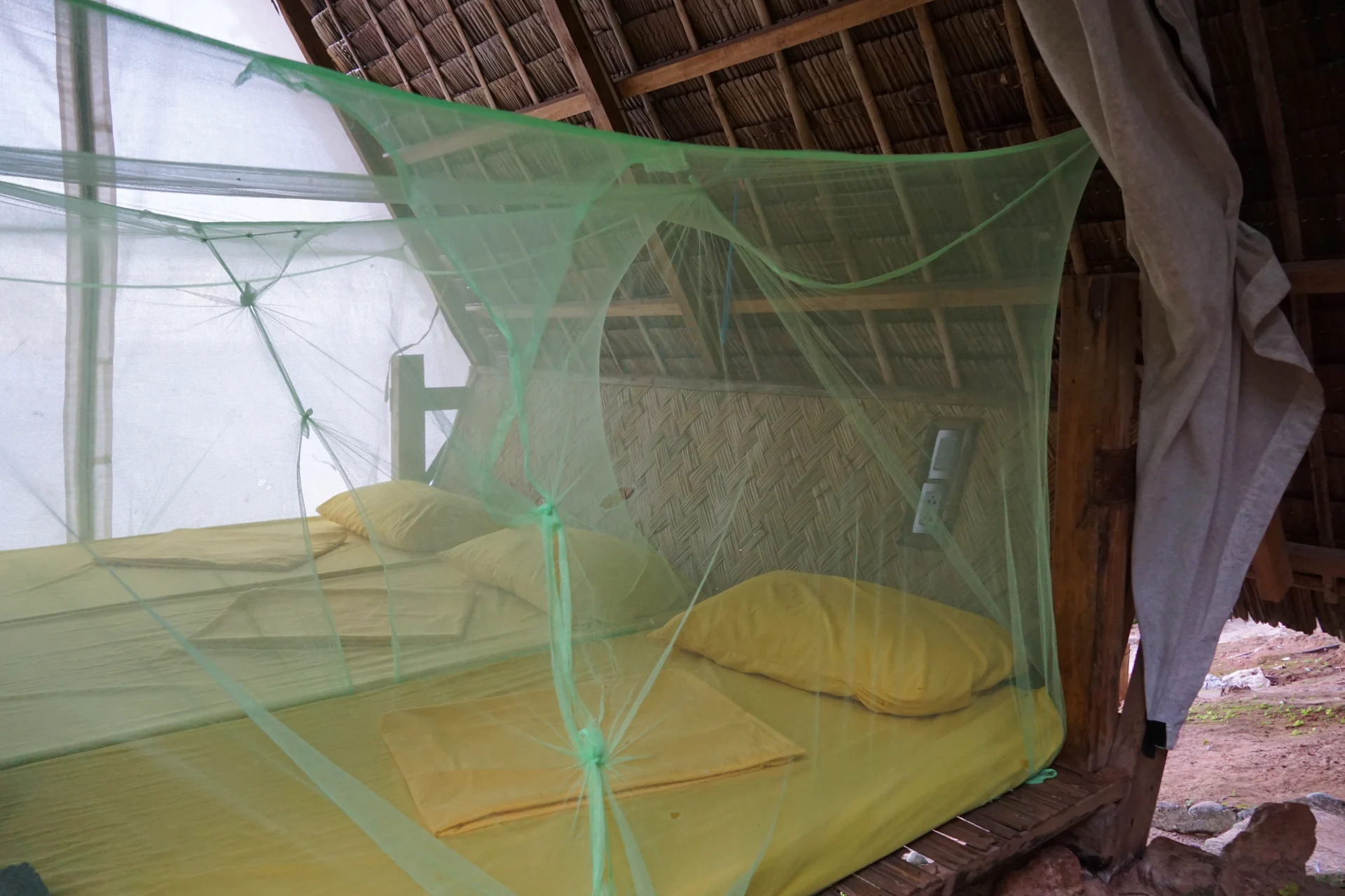 Binnenkant van een eenvoudige bahay kubo met matrassen en klamboe