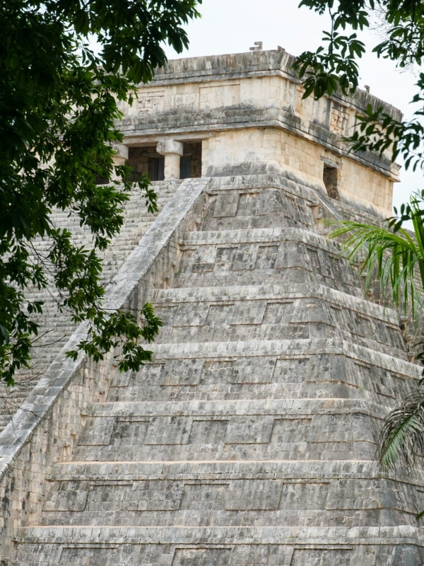 El Castillo tussen de bomen Bovenkant van El Castillo (Kukulkán piramide) in Chichén Itzá, gefotografeerd tussen groene bladeren.