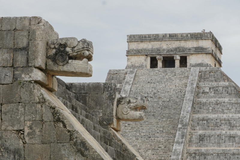 Slangenkop bij El Castillo Slangenkop aan de trapleuning met El Castillo (Kukulkán piramide) op de achtergrond in Chichén Itzá.
