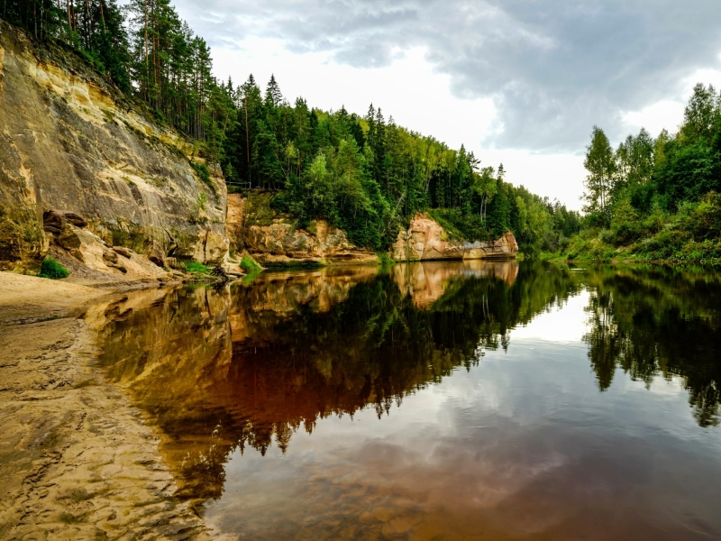 Zandsteenkliffen en spiegelend water bij de Eagle Cliffs in Gauja Nationaal Park in Letland.