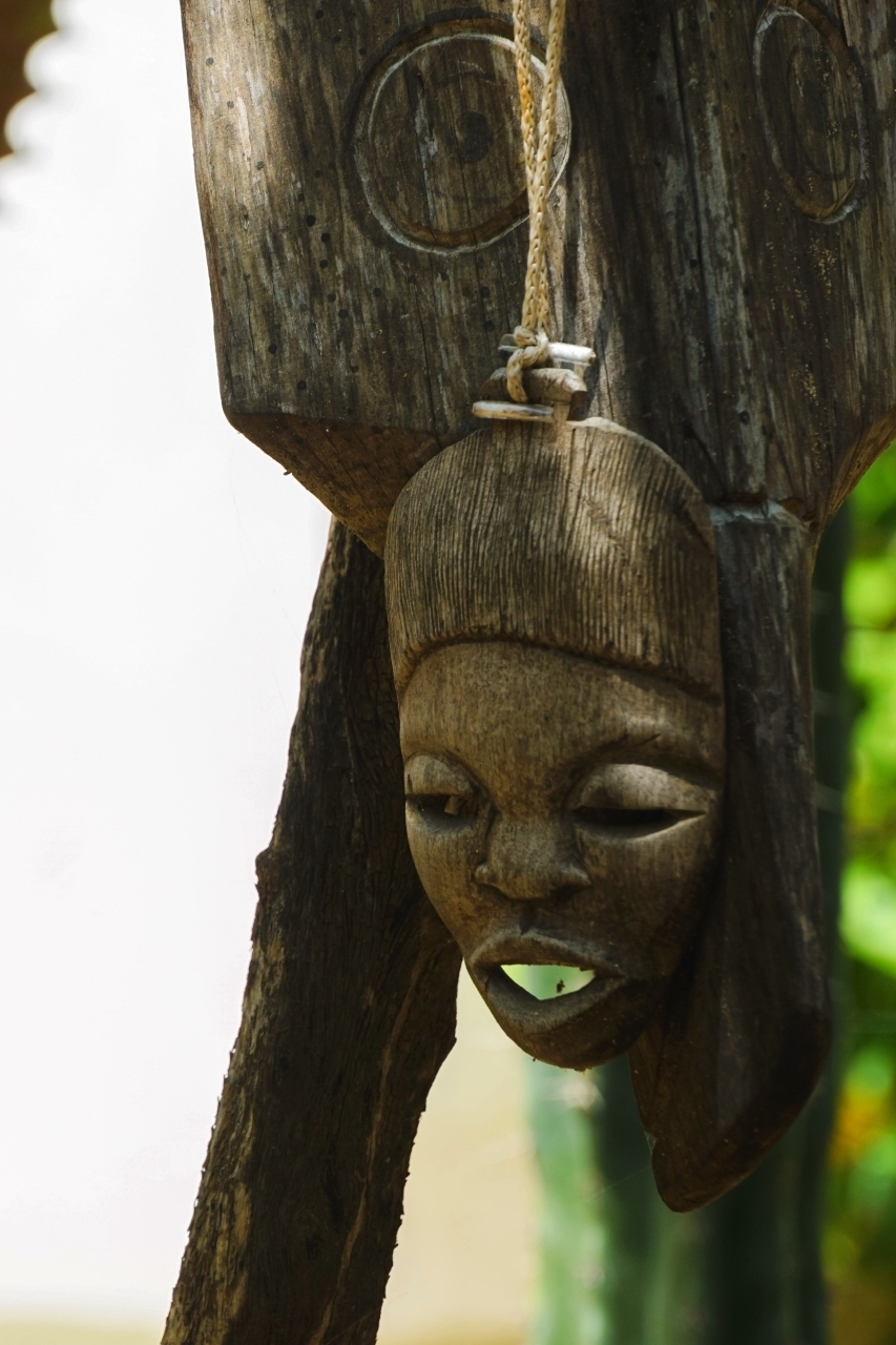 Handgemaakt houten masker hangend aan een boomstam in de tropische tuin van Un Sueño San Agustinillo Mexico