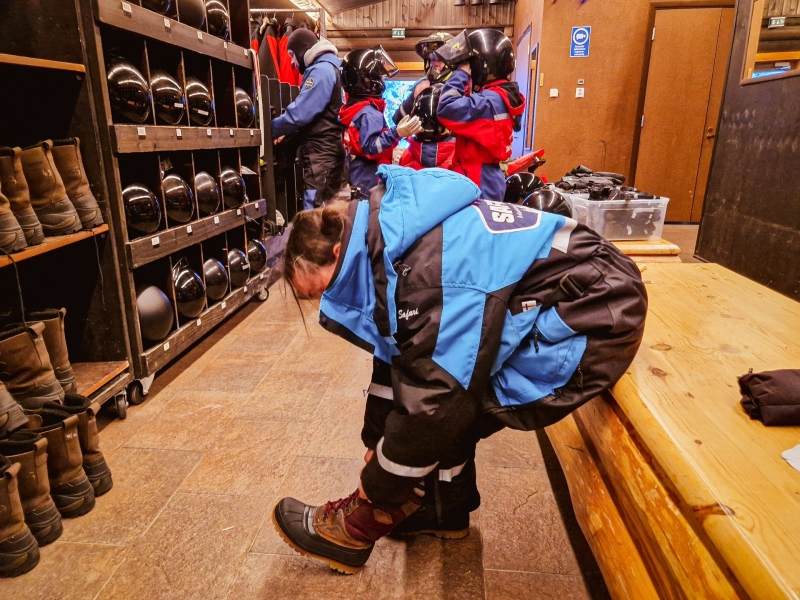 In de kleedruimte trekken gezinnen overalls en helmen aan voor een sneeuwscooter safari in Tahko