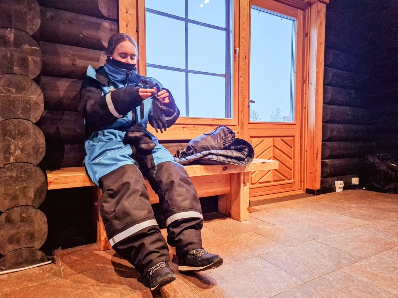 In een cabin in het bos warmen we op en trekken we handschoenen aan tijdens de sneeuwscooter tour in Tahko