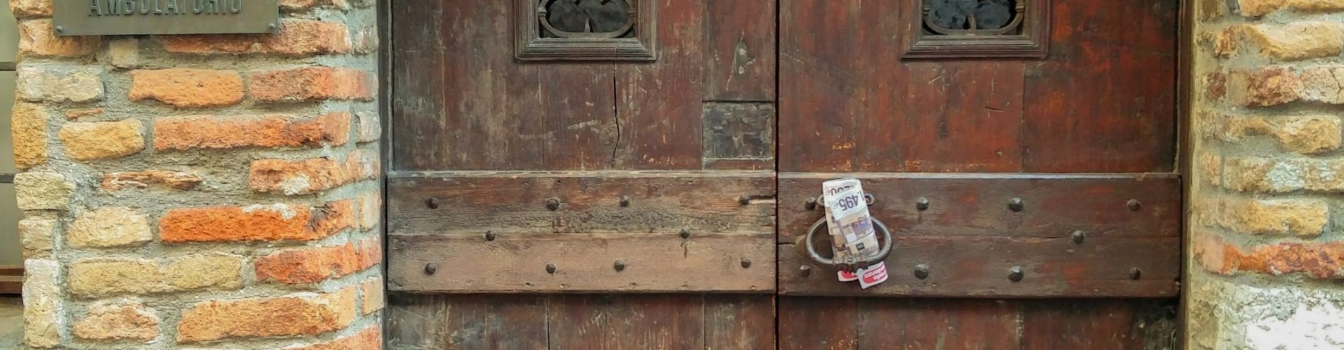 Oude houten deur in Sirmione Grote houten deur onder een stenen boog in het oude centrum van Sirmione