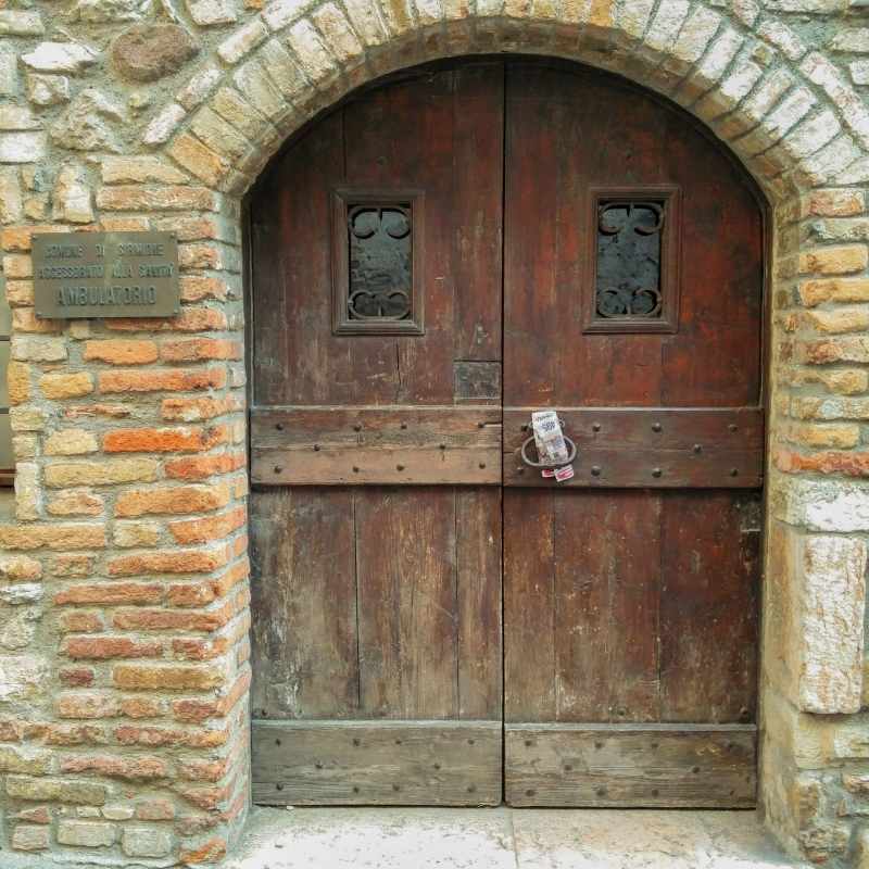 Grote houten deur onder een stenen boog in het oude centrum van Sirmione
