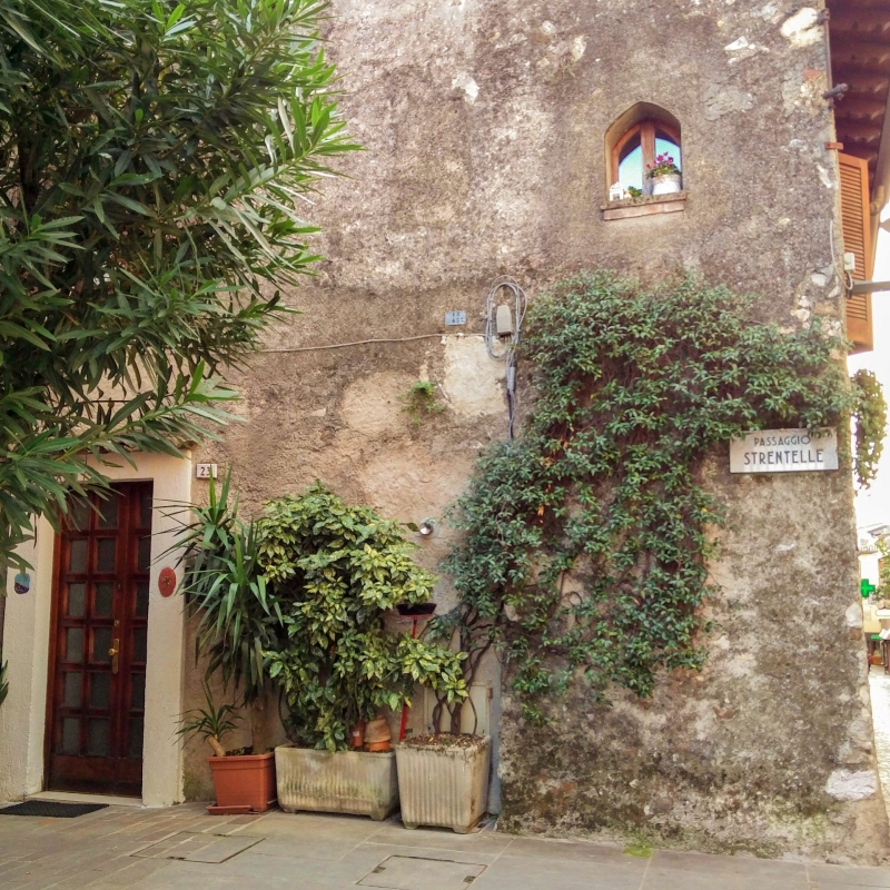Straathoek met planten en straatnaambord “Passaggio Strentelle” in Sirmione