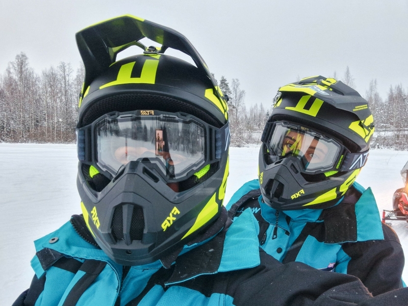 Twee deelnemers in sneeuwscooterhelm en winterpak tijdens een sneeuwscooter safari in Tahko, Finland
