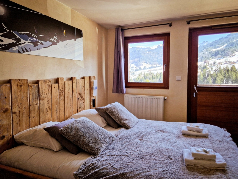 Sfeervolle slaapkamer met tweepersoonsbed en uitzicht op de bergen in Val d’Arly
