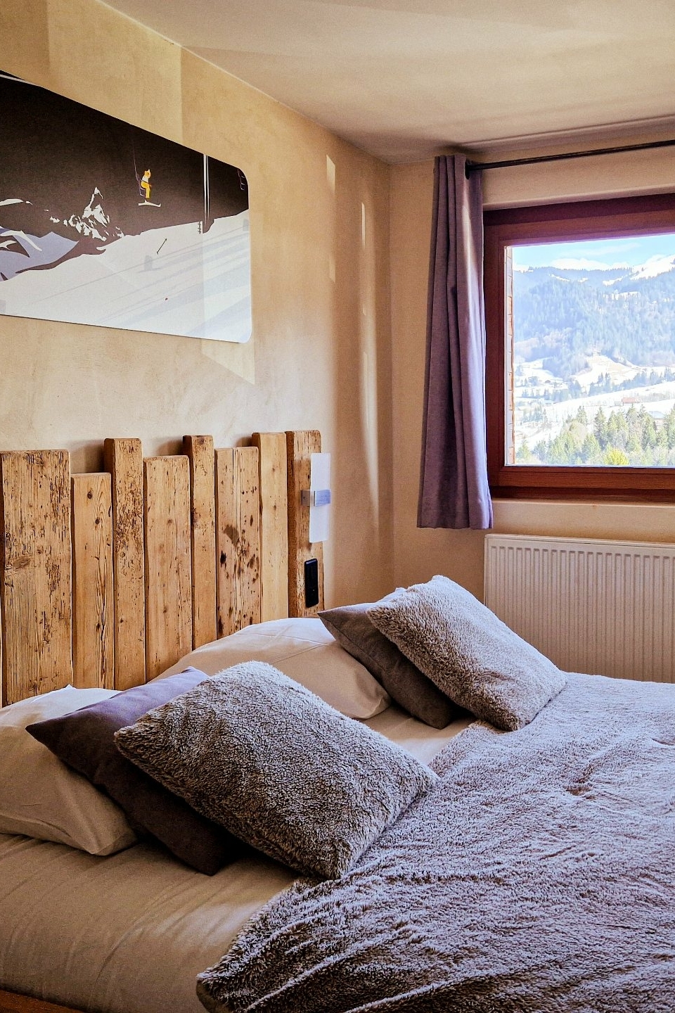 Sfeervolle slaapkamer met tweepersoonsbed en uitzicht op de bergen in Val d’Arly