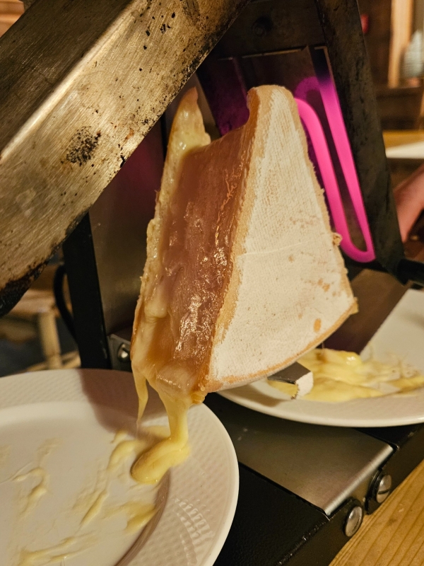 Smeltende Abondance kaas onder raclette grill tijdens wintersport diner Smeltende Abondance kaas onder raclette grill tijdens wintersport diner