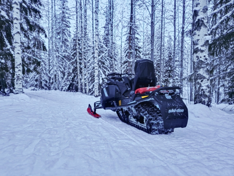 Sneeuwscooter staat stil op een besneeuwd bospad tijdens een sneeuwscooter tour in Tahko, Finland
