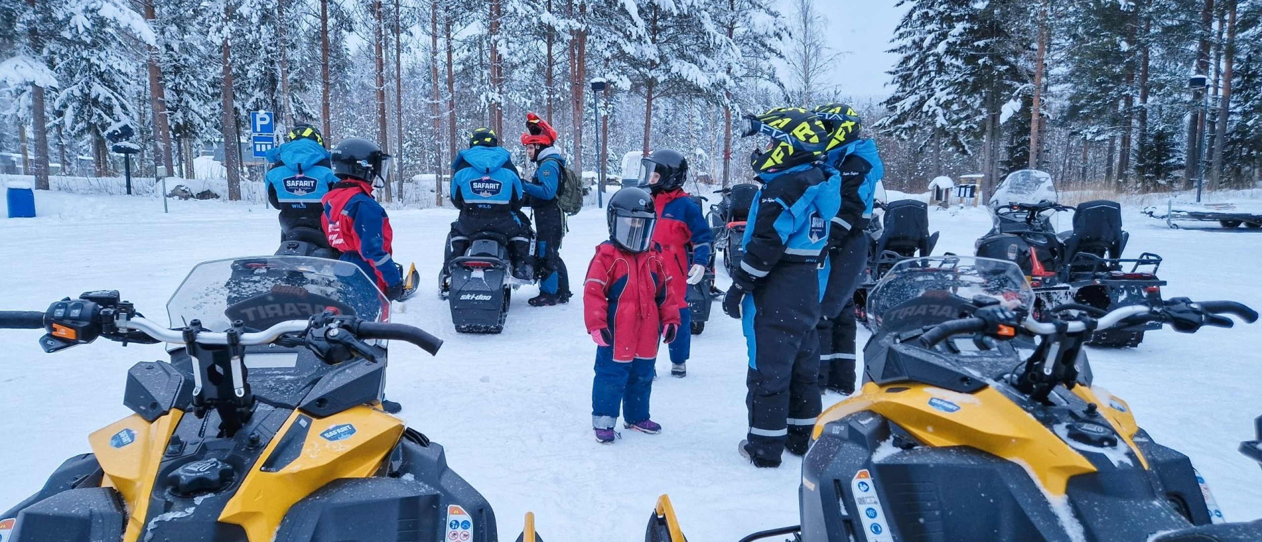 Sneeuwscooters staan klaar terwijl de groep instructies krijgt bij de start van de sneeuwscooter tour in Tahko